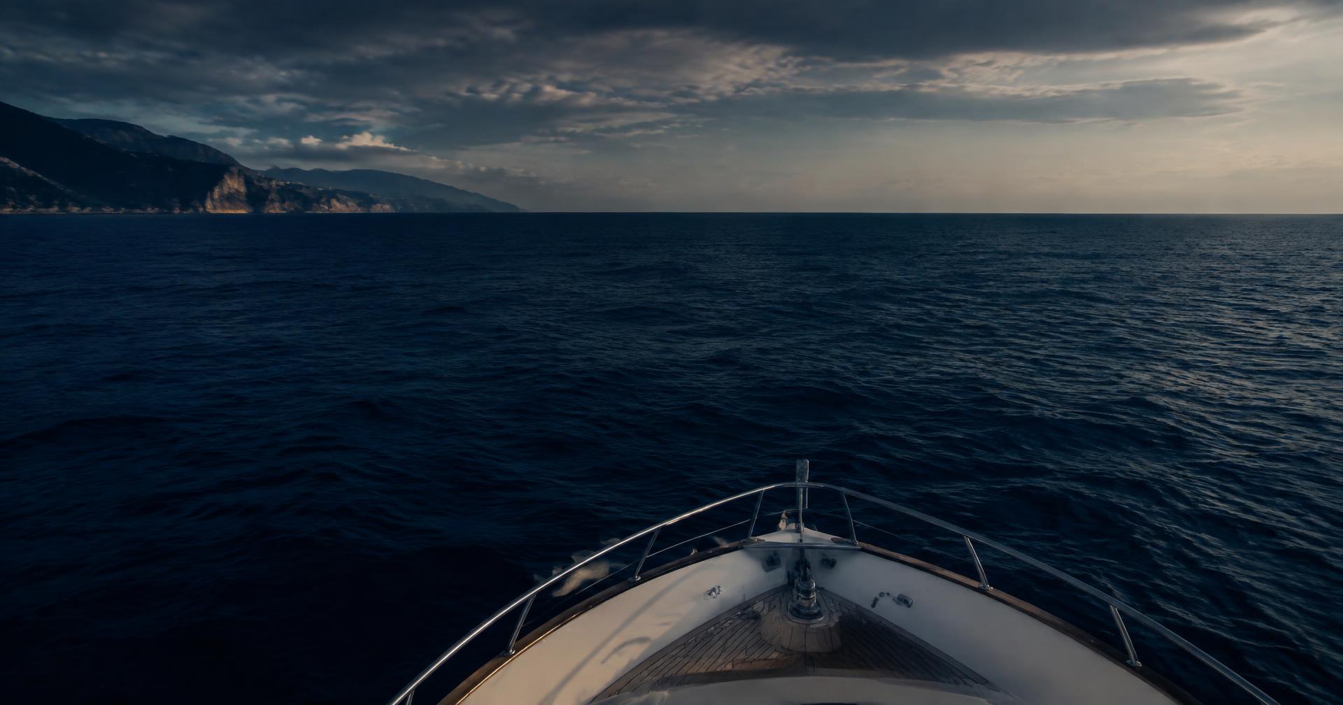 Yacht bow heading into open Mediterranean water at dusk